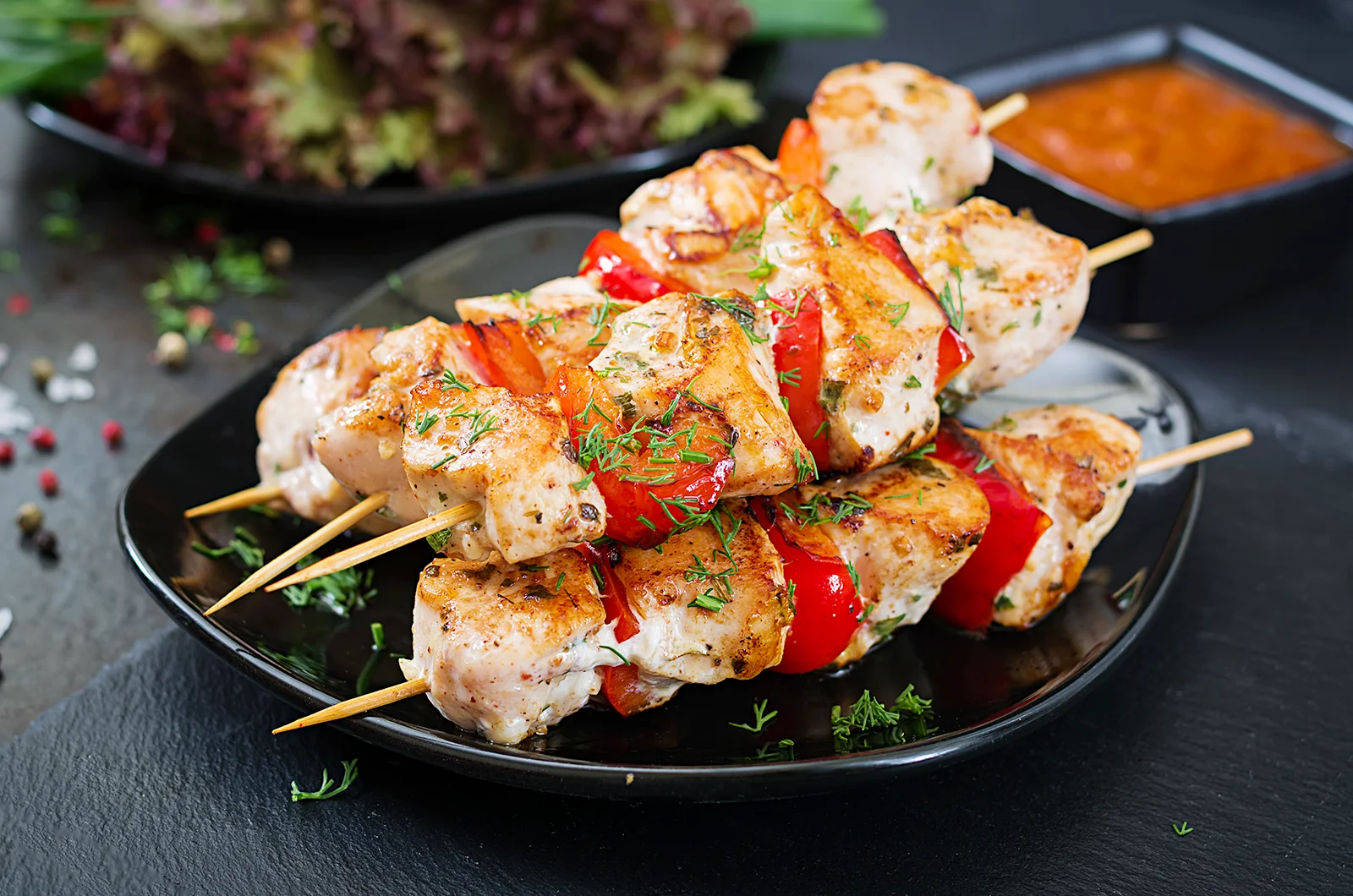 Chicken skewers presented on a black plate
