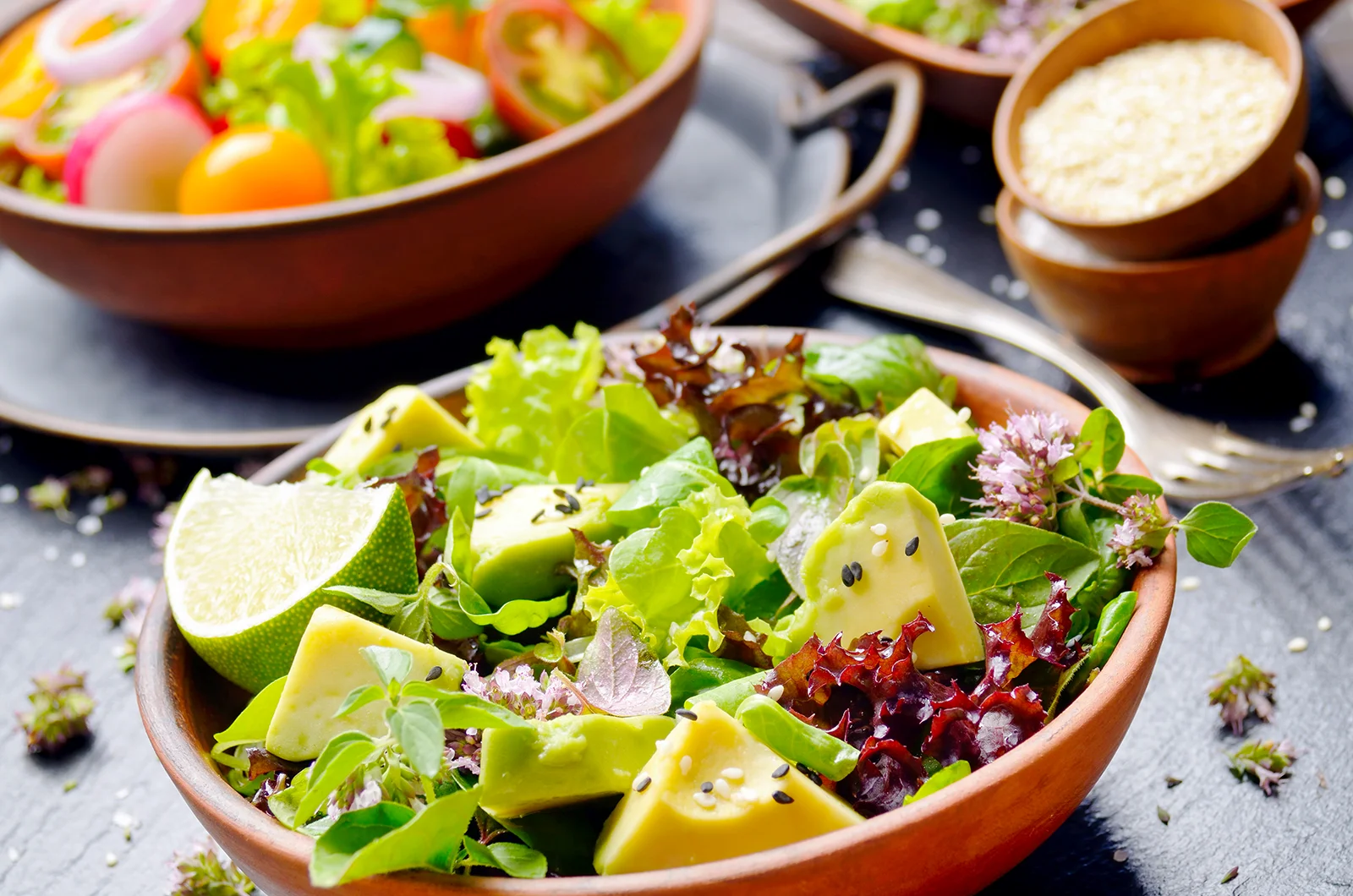 Fresh green salad with avocado, mixed greens in a wooden bowl.
