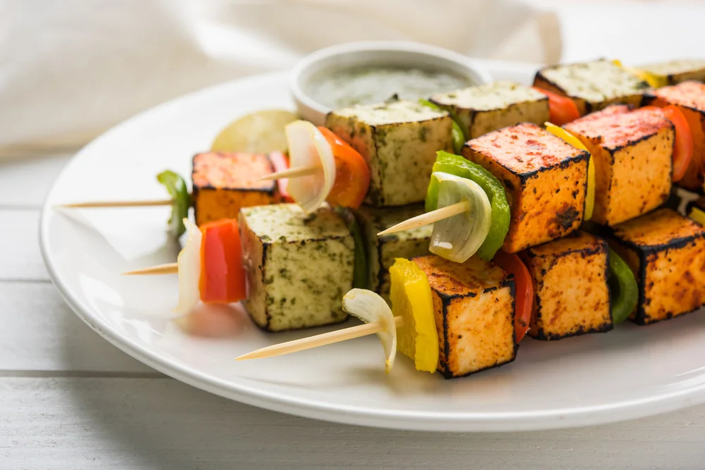 A plate of tandoori paneer tikka featuring golden, charred cubes of paneer