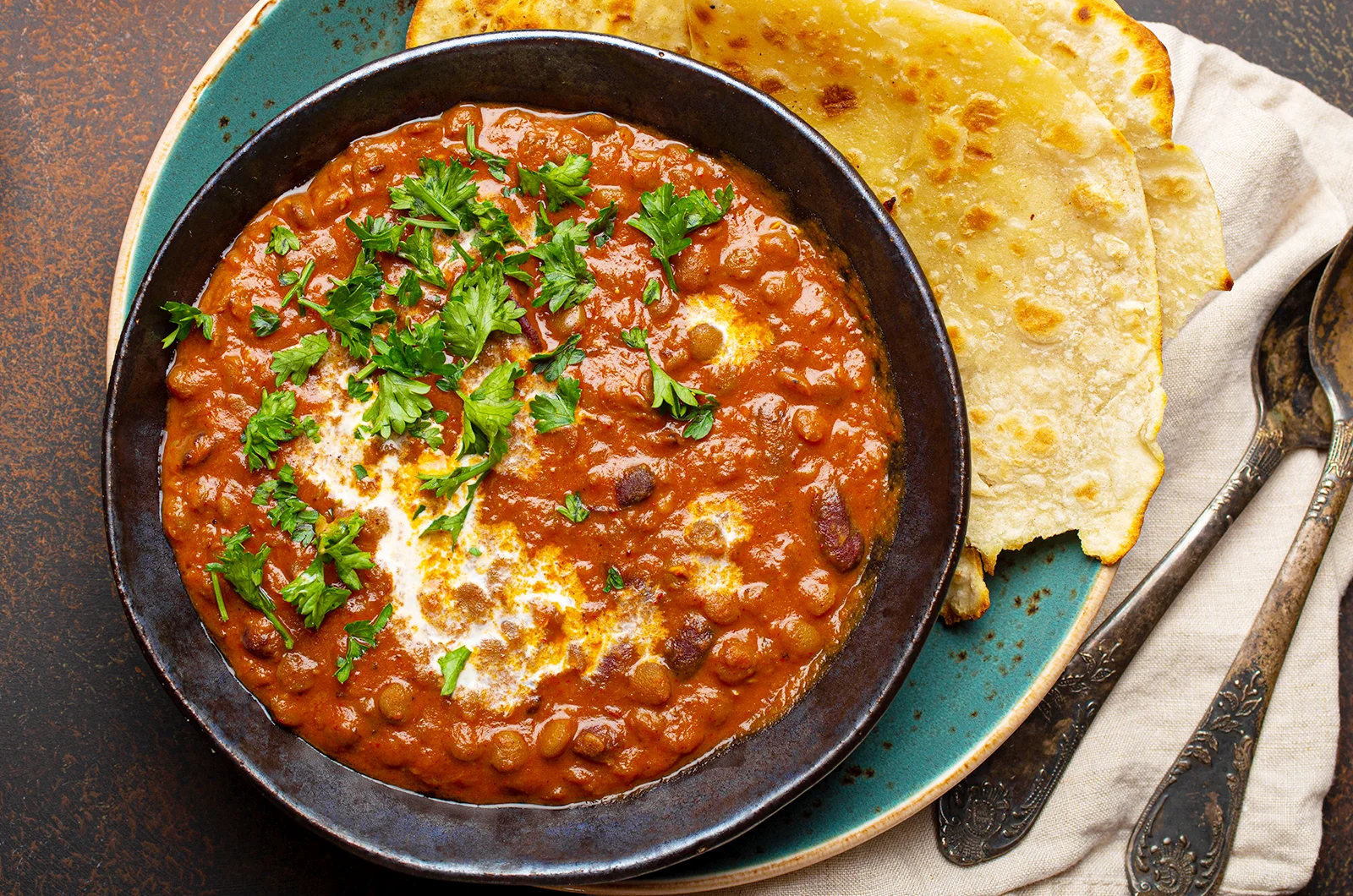 Daal Makhani garnished with cream and cilantro, served with naan bread.